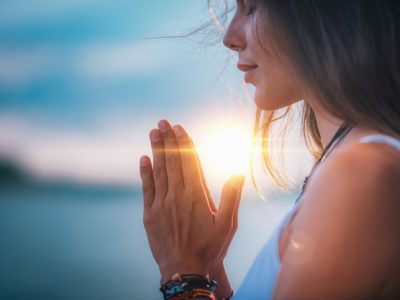 Young woman meditating with her eyes closed, practicing Yoga with hands in prayer position.